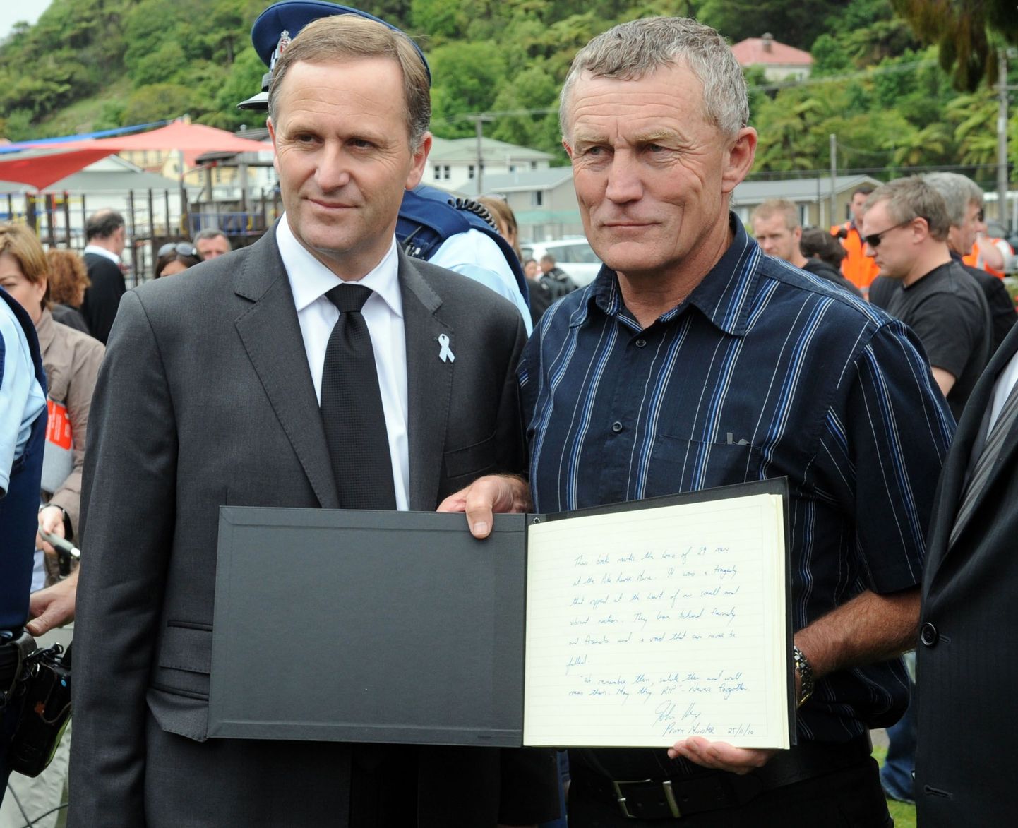 Uus-Meremaa peaminister John Key (vasakul) ja Greymouthi linnapea Tony Kokshoorn kaastundeavalduste raamatut näitamas