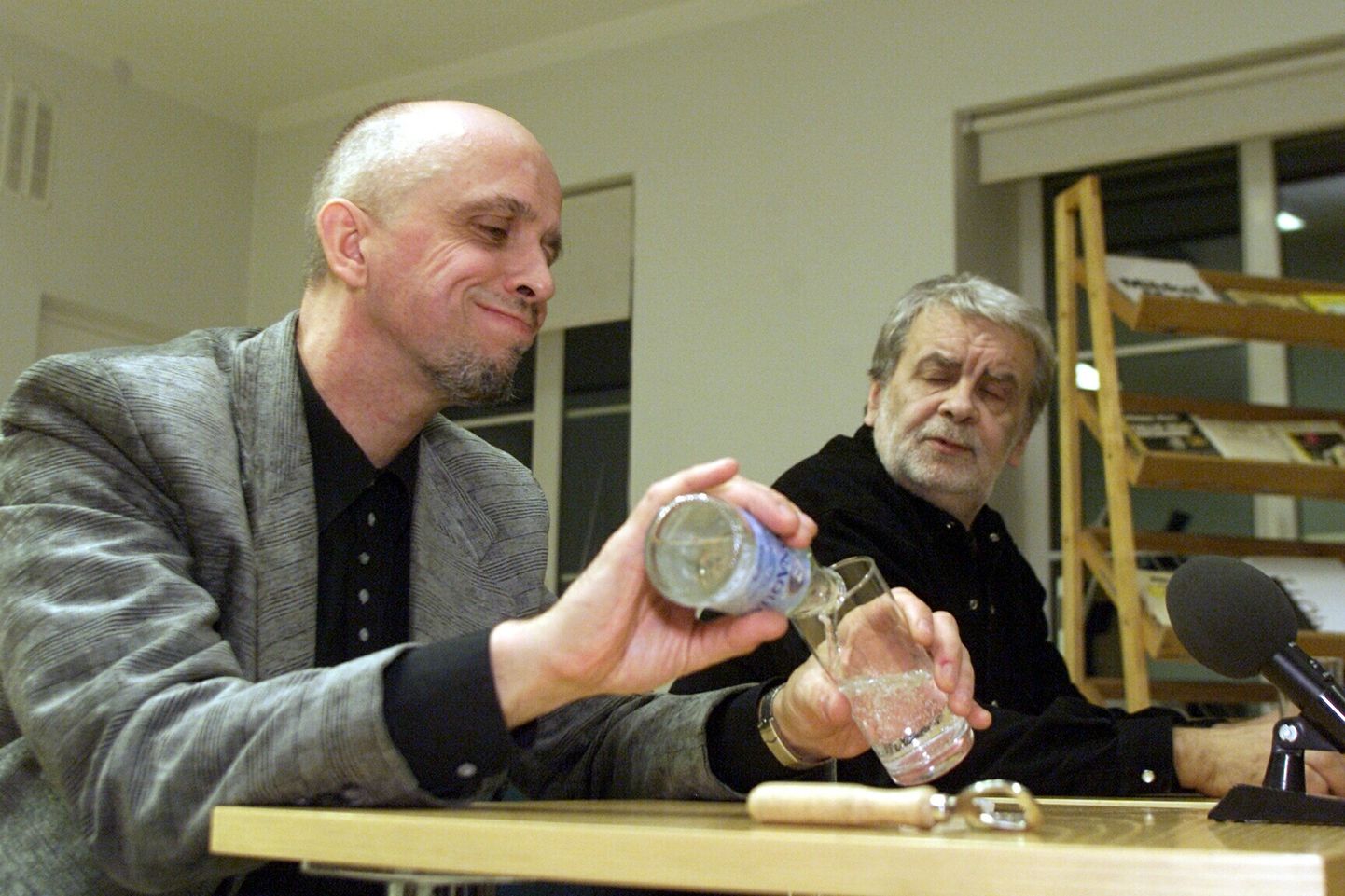 Mihkel Mutt kallab 9. novembril 2000 Tartu linnaraamatukogus kohtumisõhtul lugejatega klaasi karastusjooki. Mati Undi pilgust võib arvata, et ka tema kurk on kuiv.