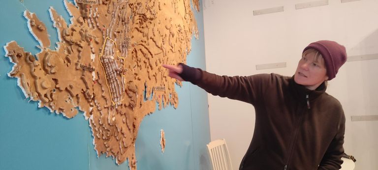 Anni Filippov, Riigimetsa Majandamise Keskuse külastuskorraldusosakonna teabetöötaja Saaremaal, näitab Saarema reljeefset kaarti seina peal. Vaatame, kuhu samme seadma hakkame. Näpp peatub Alliksoo õpperajal.