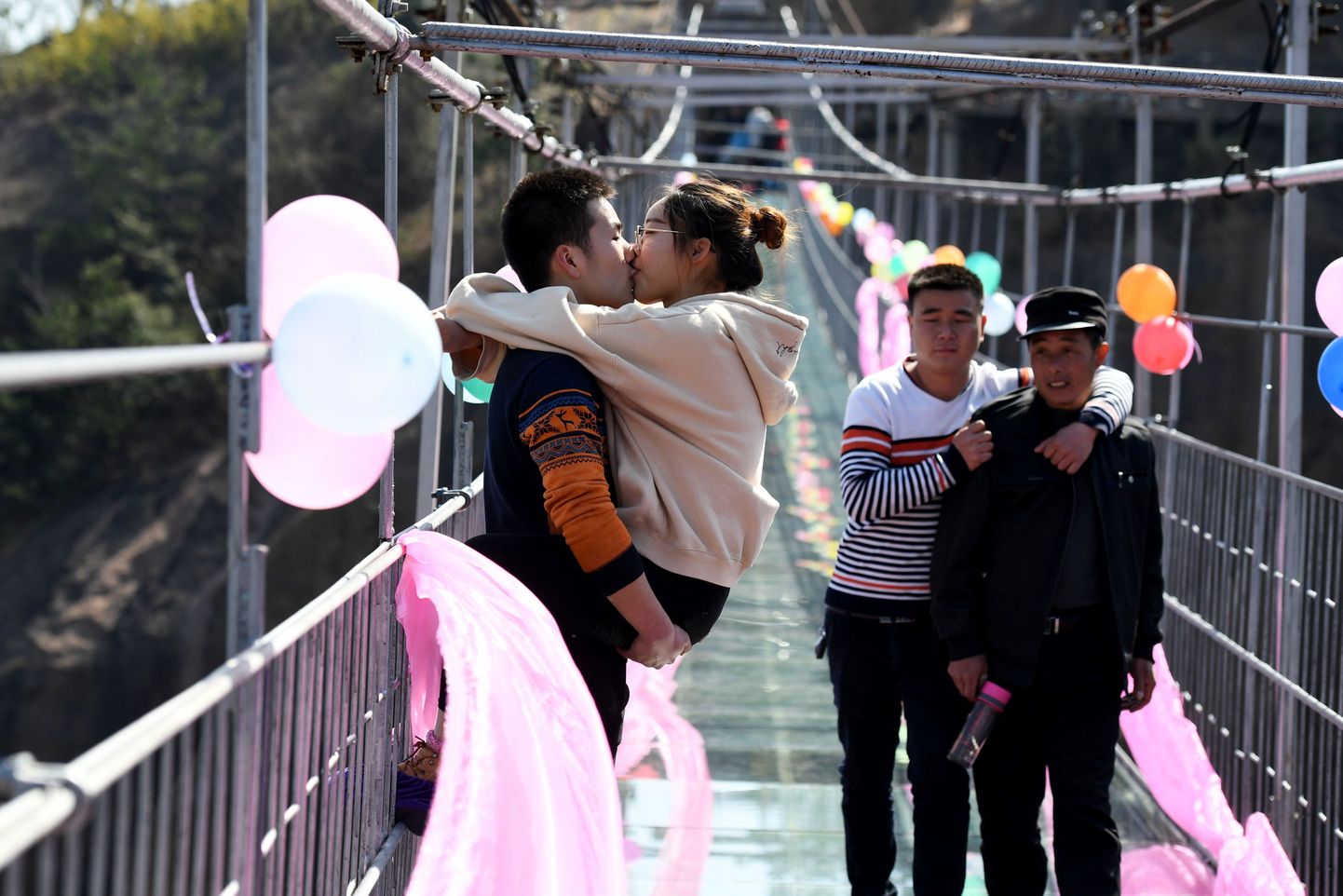 Китайская пара целуется, стоя на стеклянном мосту во время конкурса поцелуев в День святого Валентина в Пинцзяне, провинция Хунань в центральном Китае.