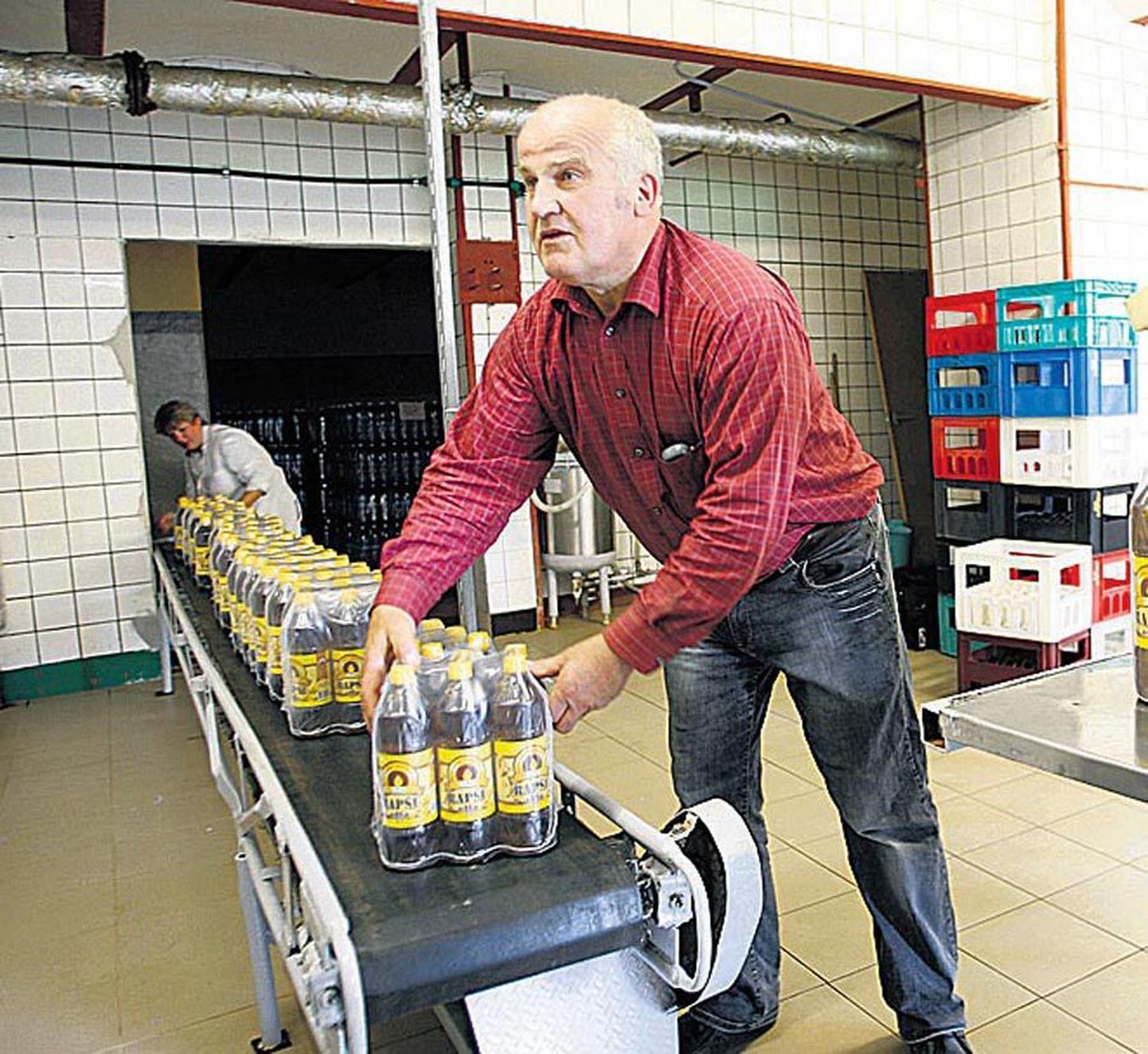 Janis Zalite pilgu all pakib automaatliin täidetud pudeleid kilesse.