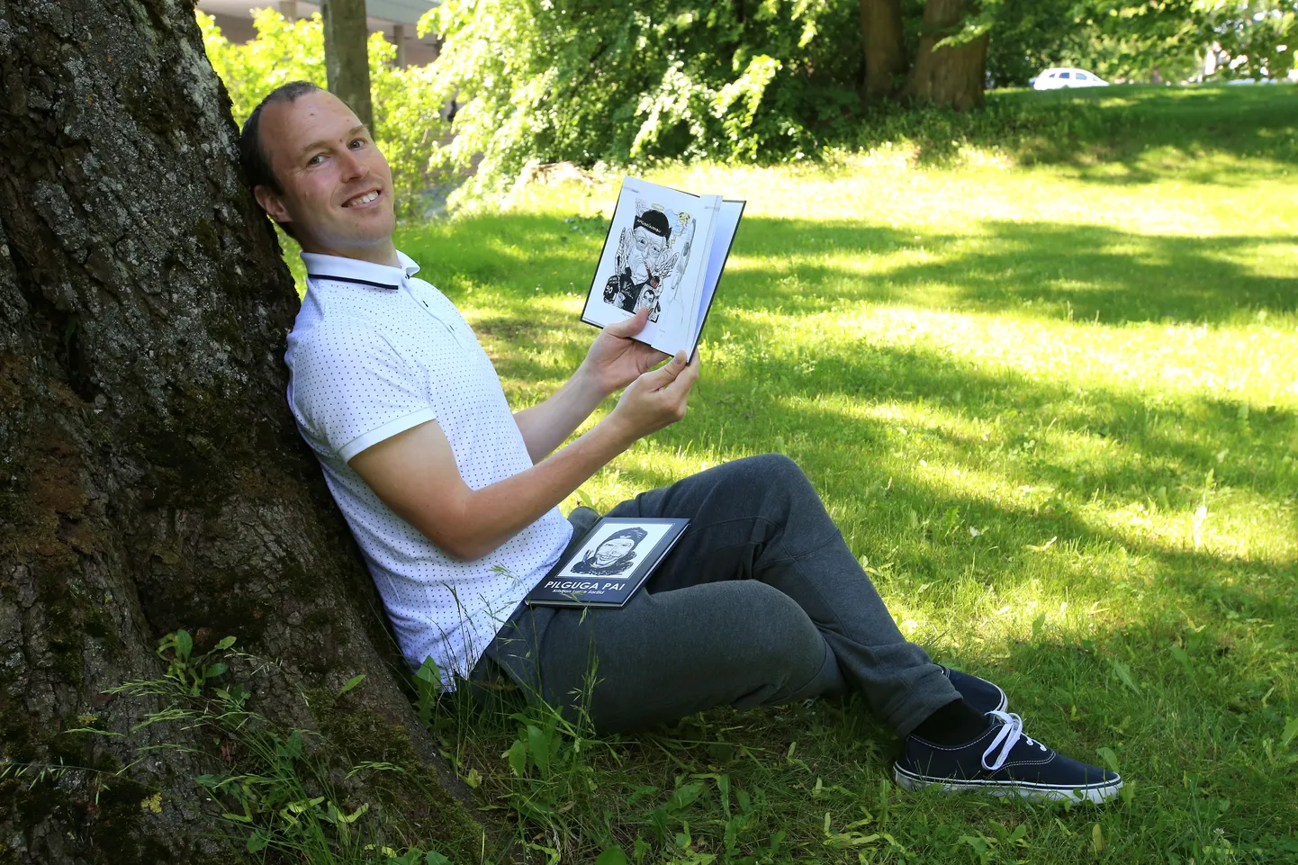 Kristjan Lume näitab oma raamatust lehekülge, kus on üks kolmest Hugo Hiibuse šaržist.