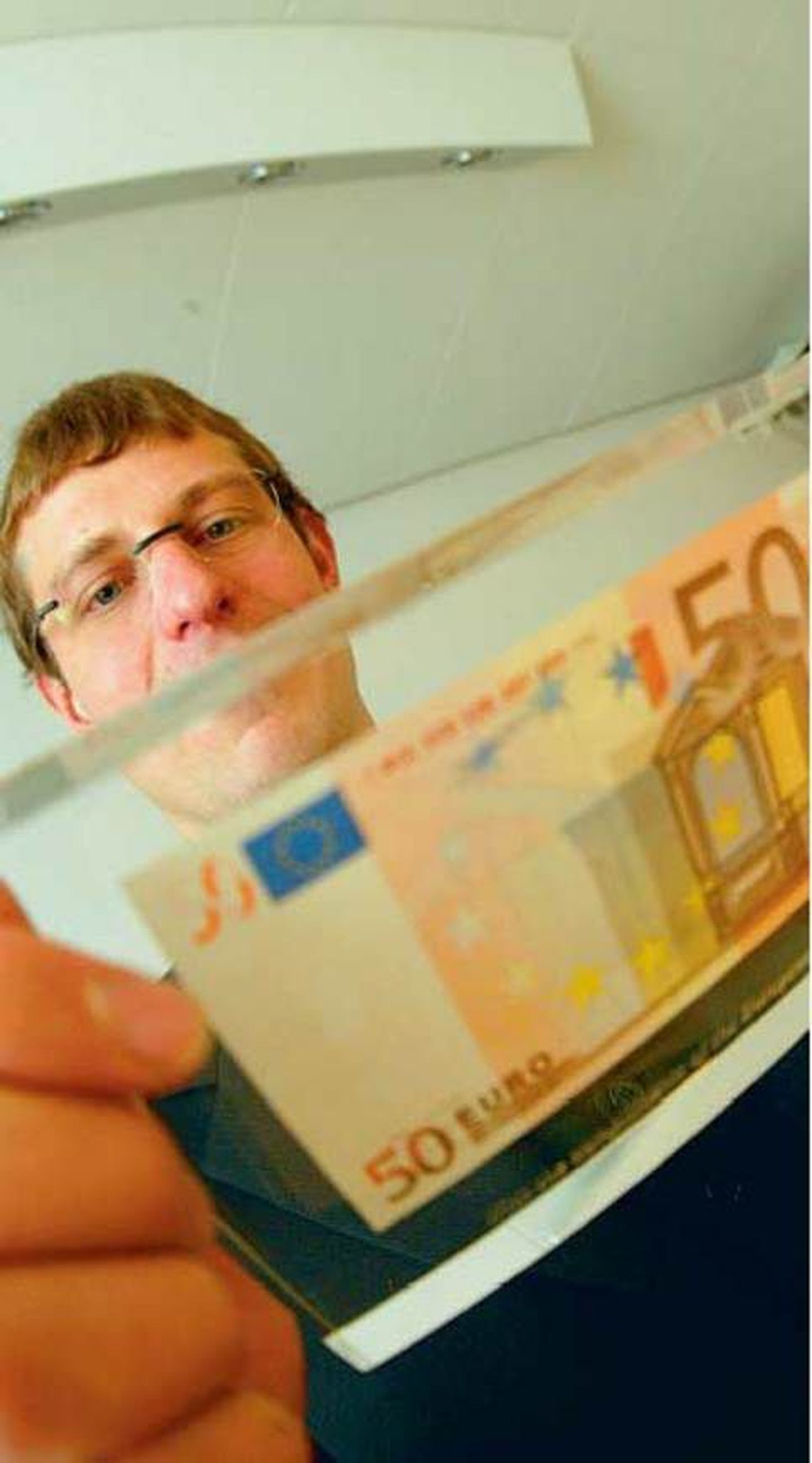 Taavi Veskimägi 2004. aastal rahandusministrina lootusrikkalt 50-eurost rahatähte uurimas..
