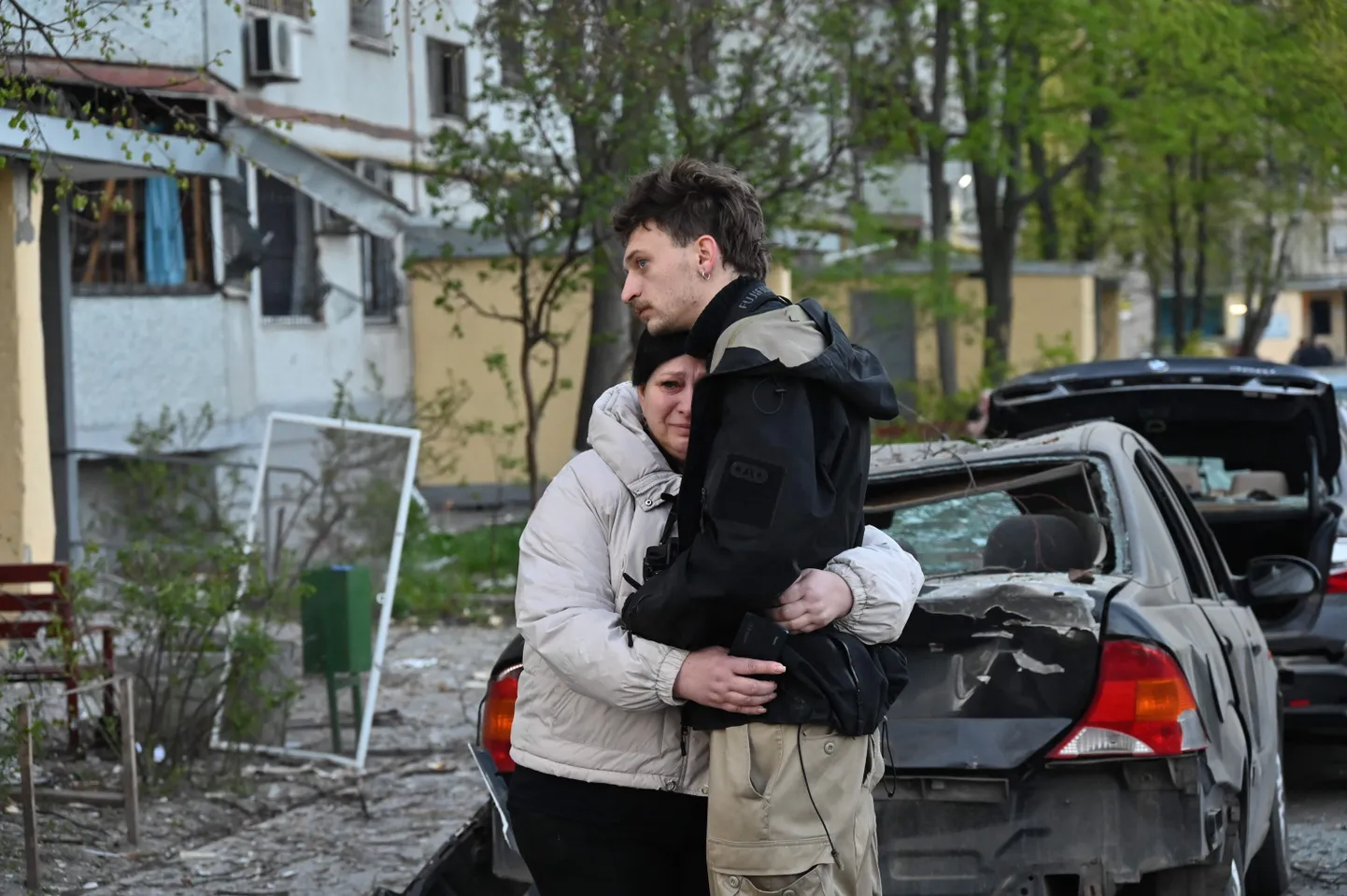 Плачущая женщина обнимает мужчину возле поврежденного дома после атак в Харькове 18 апреля 2025 года. В результате российских атак за ночь в Харькове и Сумах погибли два человека и не менее 27 получили ранения.