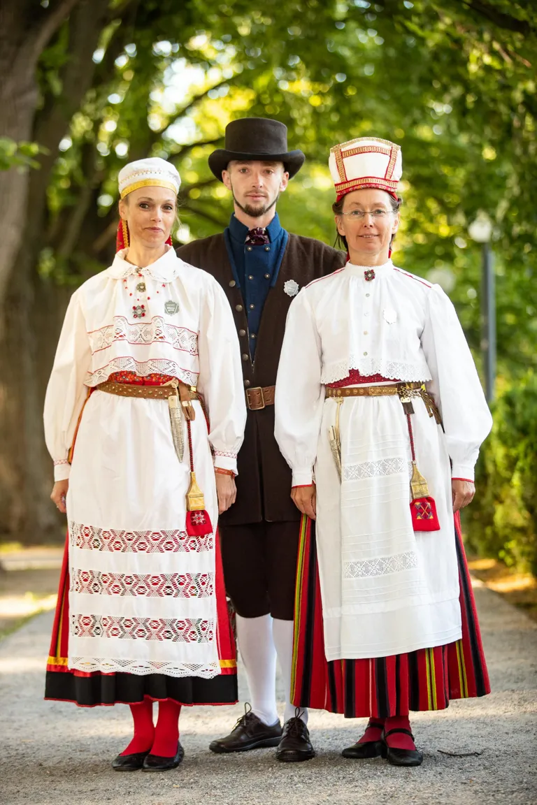 PÜHALEPA, HIIU, EMMASTE  Tiina Kaev, võimlemisrühmade liigijuhi assistent.«Minu hoole all on võimlejad ja ise olen nelja rühma juhendaja. Juured on mul mööda Hiiumaad laiali, aga sündinud-kasvanud olen Pühalepa kandis, kus praegugi elan. Uhkus ja au siin komplekti küljes on pikkade aastatega kogunenud. Riided on tädi õmmeldud, ehted on lähedased kinkinud.»Raun Zubko, S4 segarühmade liigijuht.«Hiiumaa mehe rõivad – meesterahvaste puhul ongi see üldine kõige täpsem. Kui naiste rõivad olid edevamad ja iga kant pidi ikka omamoodi triibu tegema, siis meestel oli oluline lihtsalt rõivad selga saada.»Helle-Mare Kõmmus, S4 segarühmade liigijuhi assistent.«Olen tantsupeo lavastusgrupi liige, Hiiu maakonna kuraator ning kahe tantsurühma juhendaja. Meil on naisrühm Kohvilähkrid ja segarühm Taidelaid. Eks see rahvatantsu- ja rahvarõivaarmastus on kasvanud ajaga – hiidlane kannab ikka oma riiet. Kui võrrelda esimesi pidusid ja tänast, siis täna olen palju rikkam ja rikkalikum. Detaile korjad ajaga. Olen ise Emmastest pärit juurikat pidi ja ema käest pärandina saadud rõhud on puusal.»