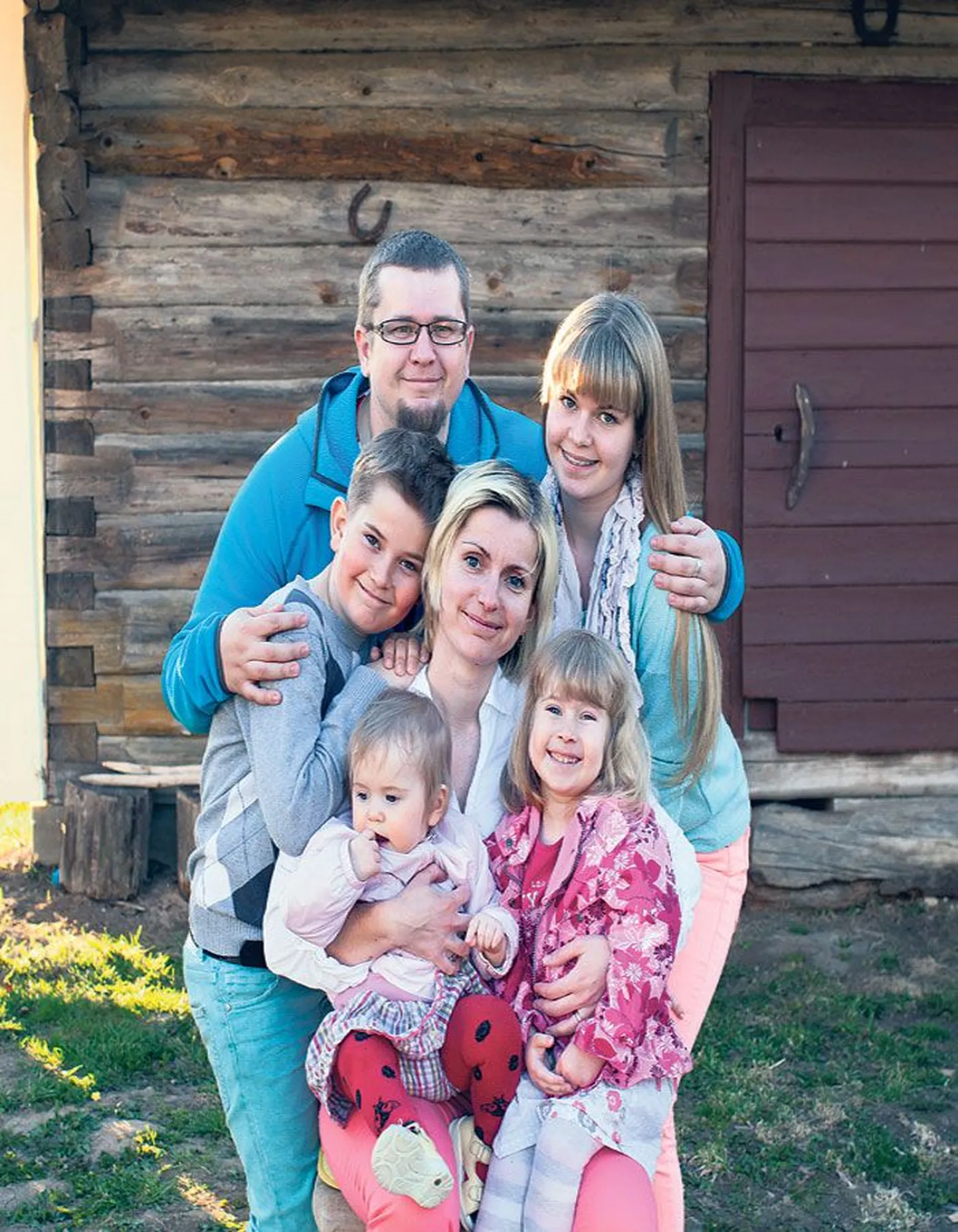 Kogu pere koduhoovil: 
keskel ema Grethe Rõõm, süles Anni (1) ja Kirke (3), taga isa Taavi Karu, tema ees Emil (9) ja Sandra (14).