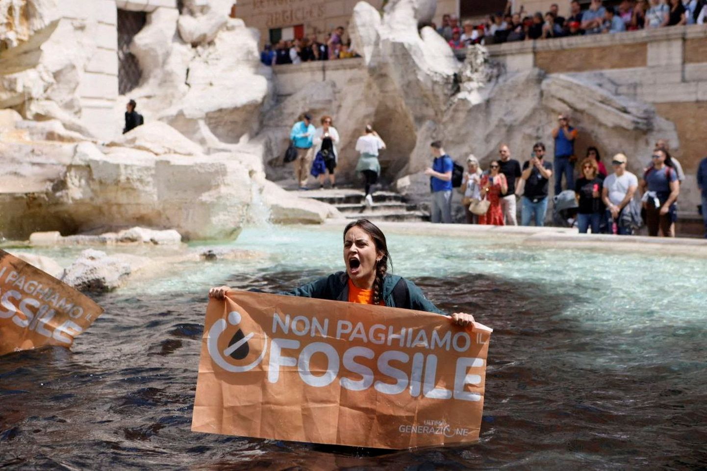 Климатический активист держит плакат в фонтане Треви в Риме.