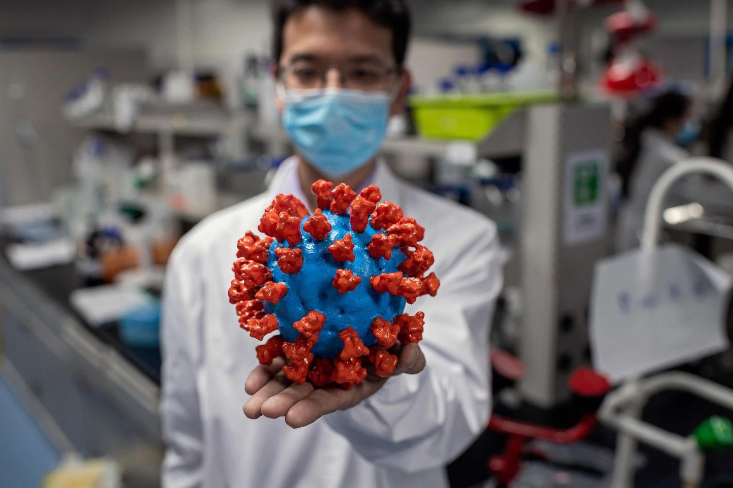 Hiina teadlane näitamas koroonaviiruse plastikmudelit.