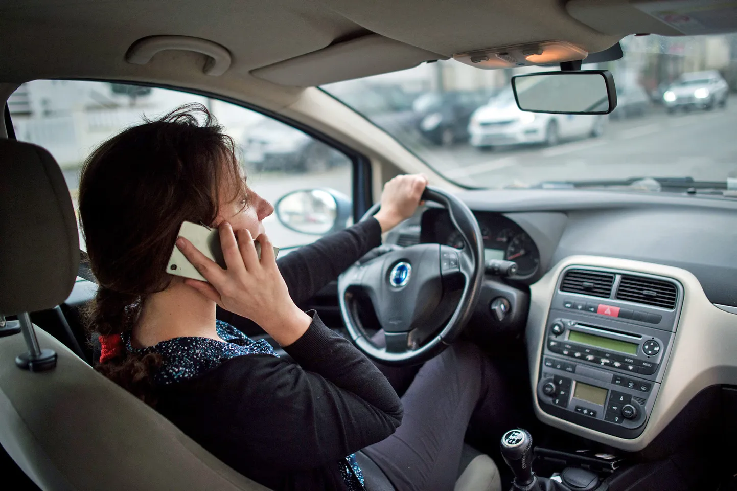 Autovadītāja lieto mobilo telefonu, atrodoties pie auto stūres