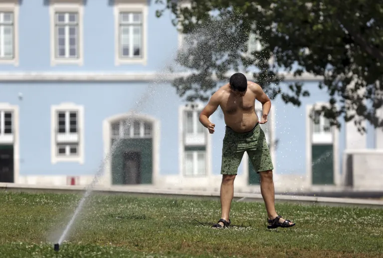 Kuumalaine Portugalis, mees end muruniisutaja all end jahutamas