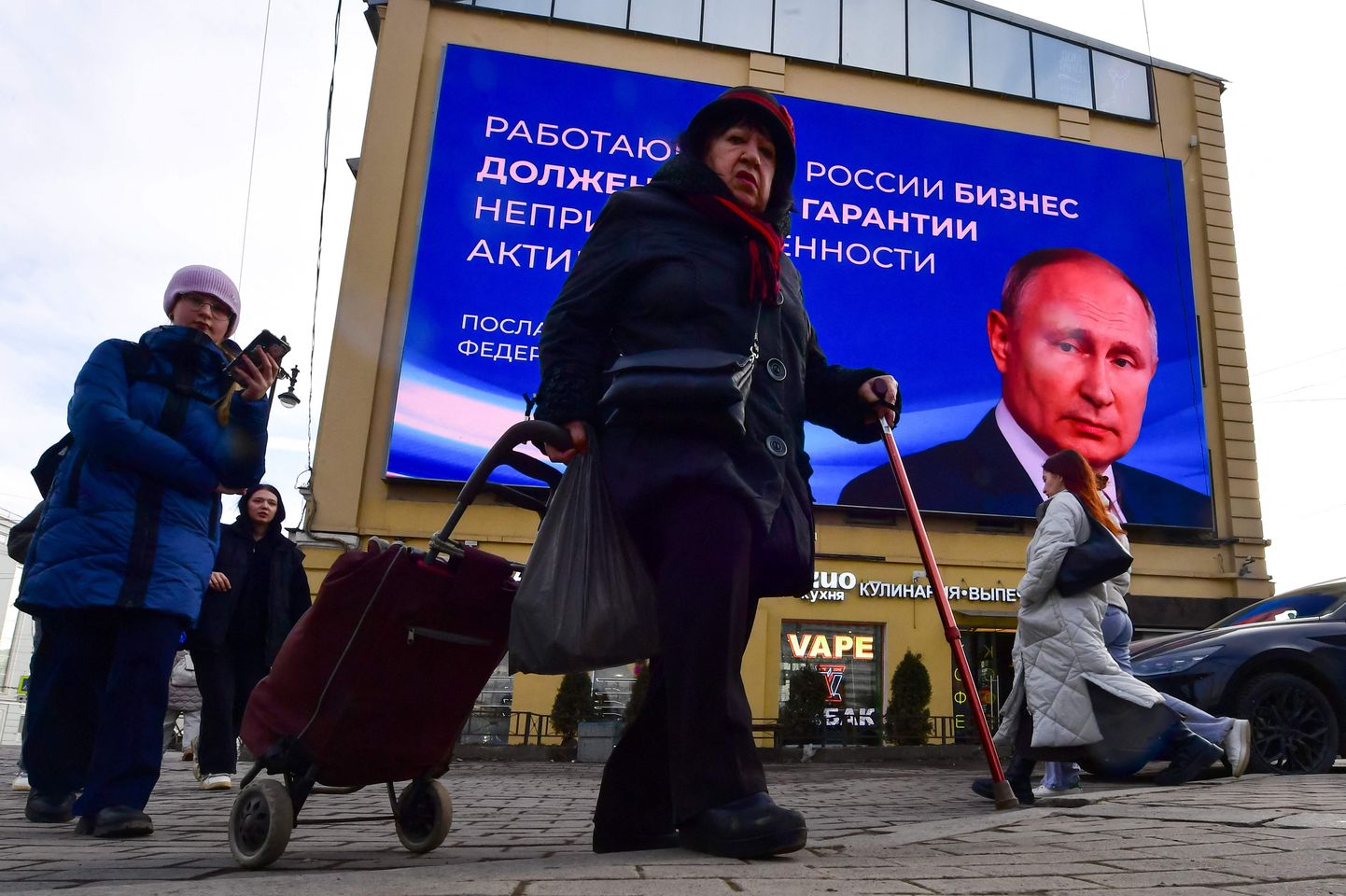 Venelannad Vladimir Putini valimisplakati taustal 13. märtsil 2024.
