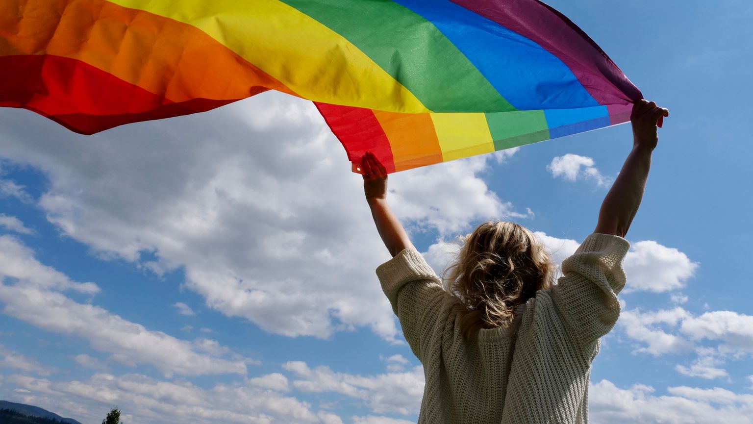 Блондинка-лесбиянка держит радужный флаг гендерной идентичности ЛГБТ. Фото иллюстративное.