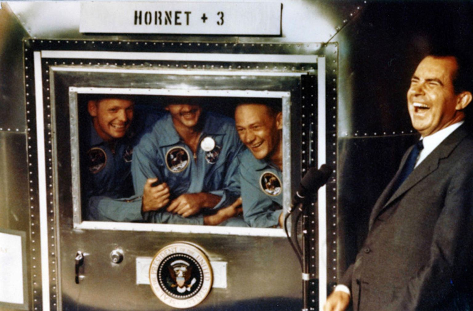 USA president Richard Nixon (paremal) tervitab 24. juulil 1969 lennukikandja USS Hornet pardal äsja Kuu-missioonilt naasnud Apollo 11 meeskonnaliikmeid (vasakult) Neil Armstrongi, Michael Collinsit ja Buzz Aldrinit.