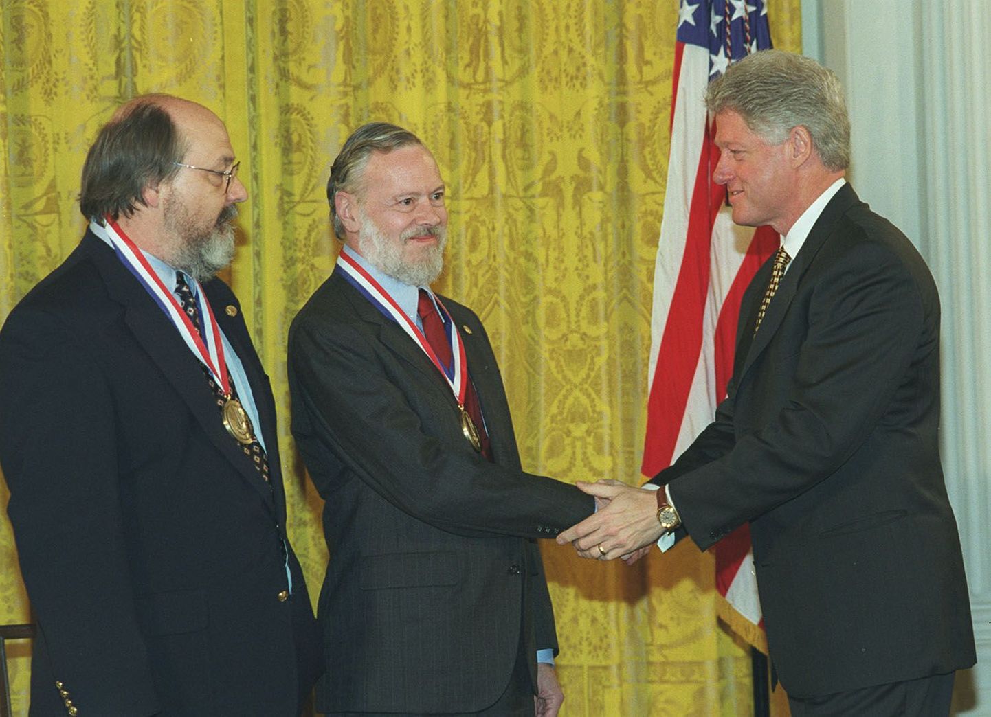 Деннис Ритчи (в центре) и Кен Томпсон (слева) получают Национальную медаль США за достижения в области технологий и инноваций 1998 года из рук президента Билла Клинтона