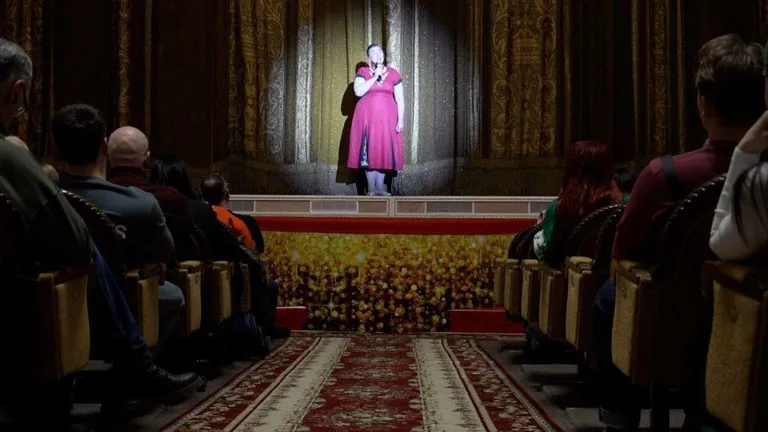 Женщина в розовом платье на сцене театра.
