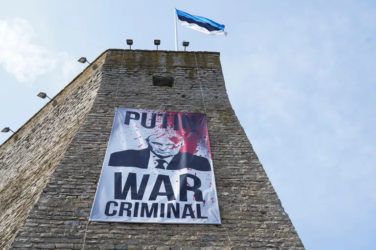 Плакат «Путин – военный преступник» на Нарвской крепости 9 мая 2023 года – один из самых публичных примеров гибридной войны Эстонии против России. Публичность и прозрачность можно считать особенностью гибридной войны в Эстонии.