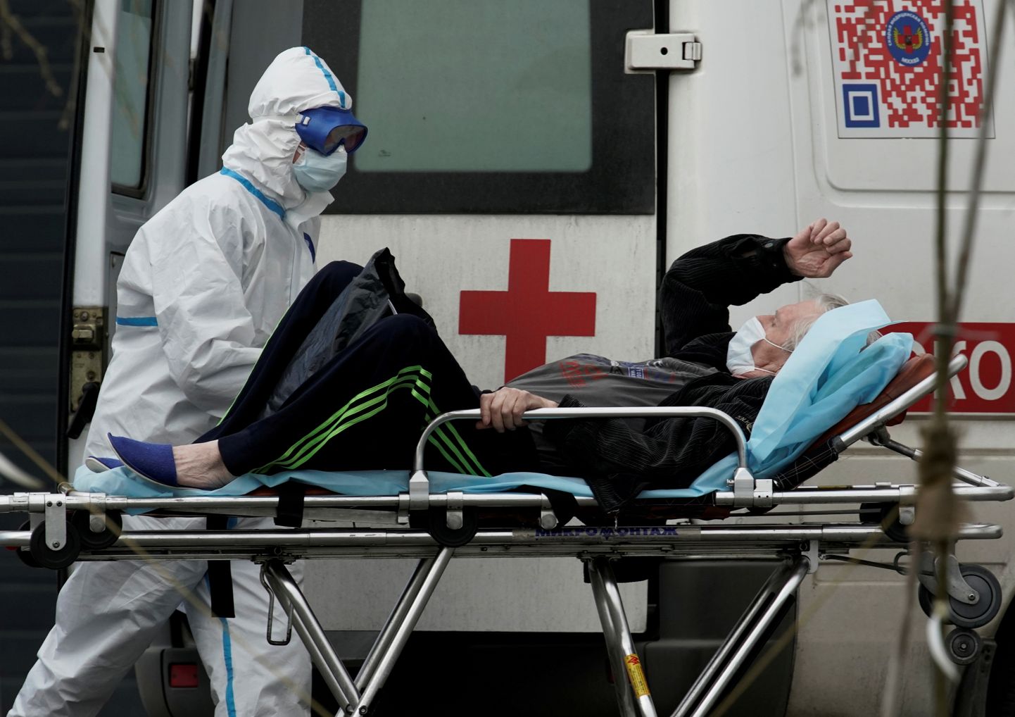Kaitseriietuses meditsiinitöötaja toimetab koroonahaige Moskvas kiirabiautost haiglasse.