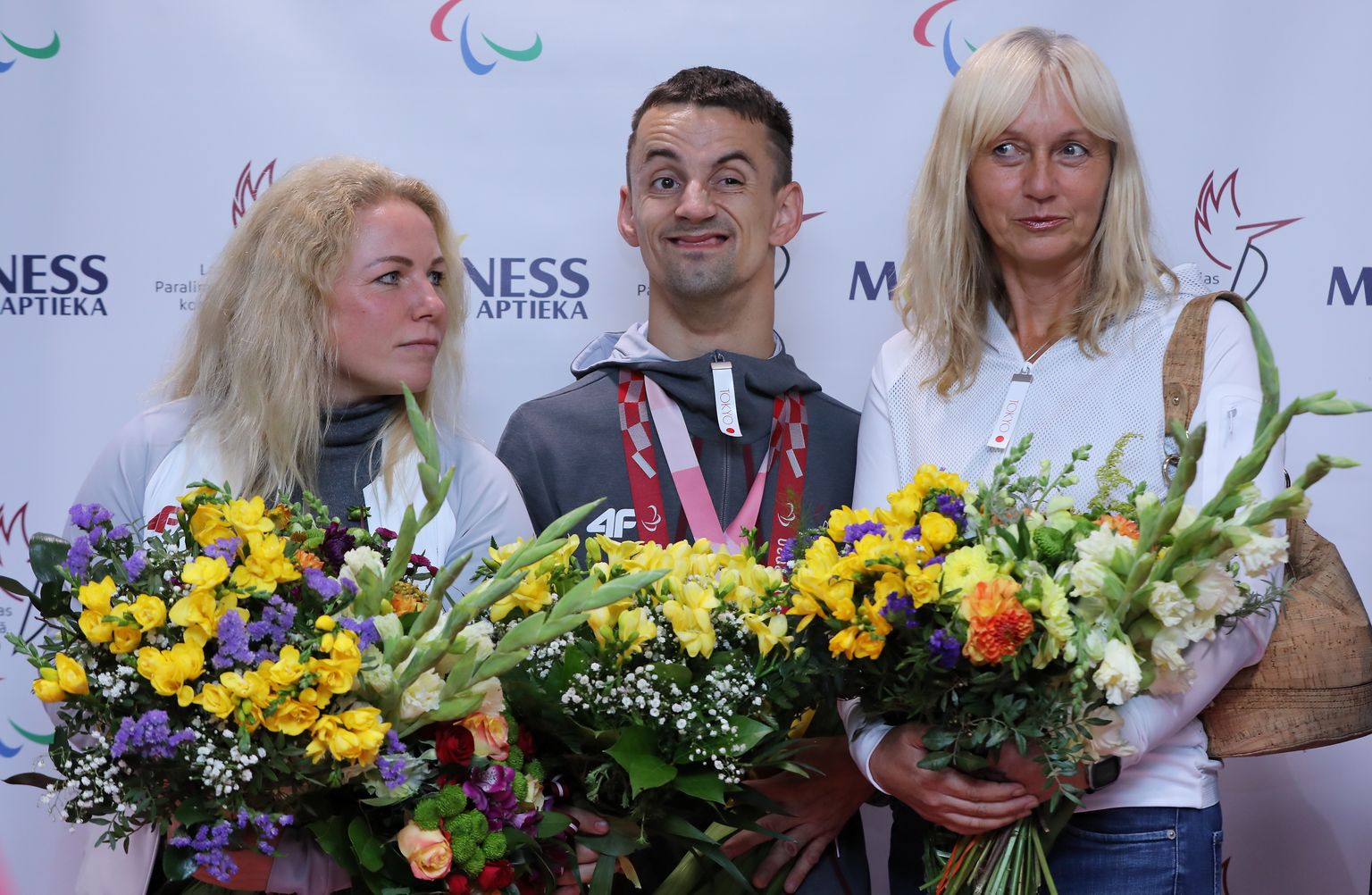 Trenere Darja Tihomirova, divkārtējais sudraba medaļu ieguvējs, paralimpiskais jātnieks Rihards Snikus un pirmā trenere Olga Šillere lidostā "Rīga", atgriežoties no Tokijas paralimpiskajām spēlēm.