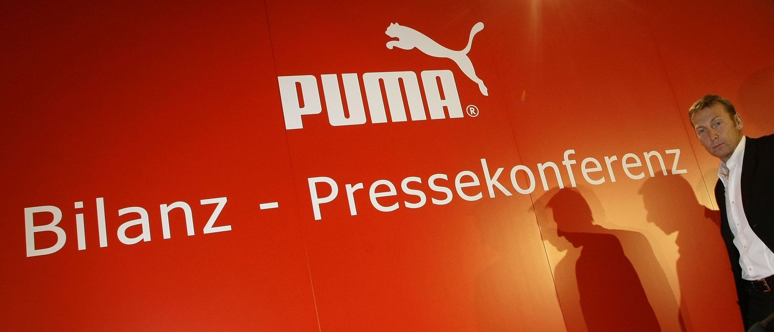 Puma tegevjuht Jochen Zeitz firma logoga plakati juures.