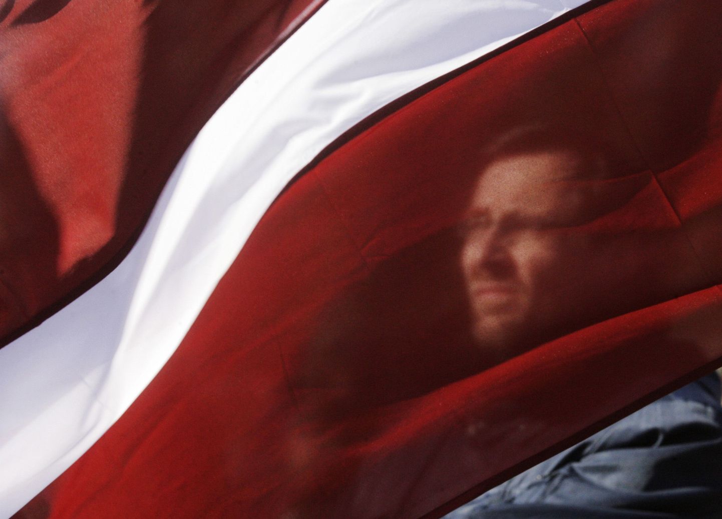 A man holds a Latvian national flag during a procession commemorating the Latvian Waffen SS unit, also known as the Legionnaires, in Riga March 16, 2011. The Legionnaires are being commemorated for fighting against the Soviet occupation of Latvia but the Nazi connection has caused great controversy abroad, particularly in Russia. About 1,000 people participated in the event, according to local media. REUTERS/Ints Kalnins (LATVIA - Tags: POLITICS CIVIL UNREST ANNIVERSARY MILITARY IMAGES OF THE DAY)