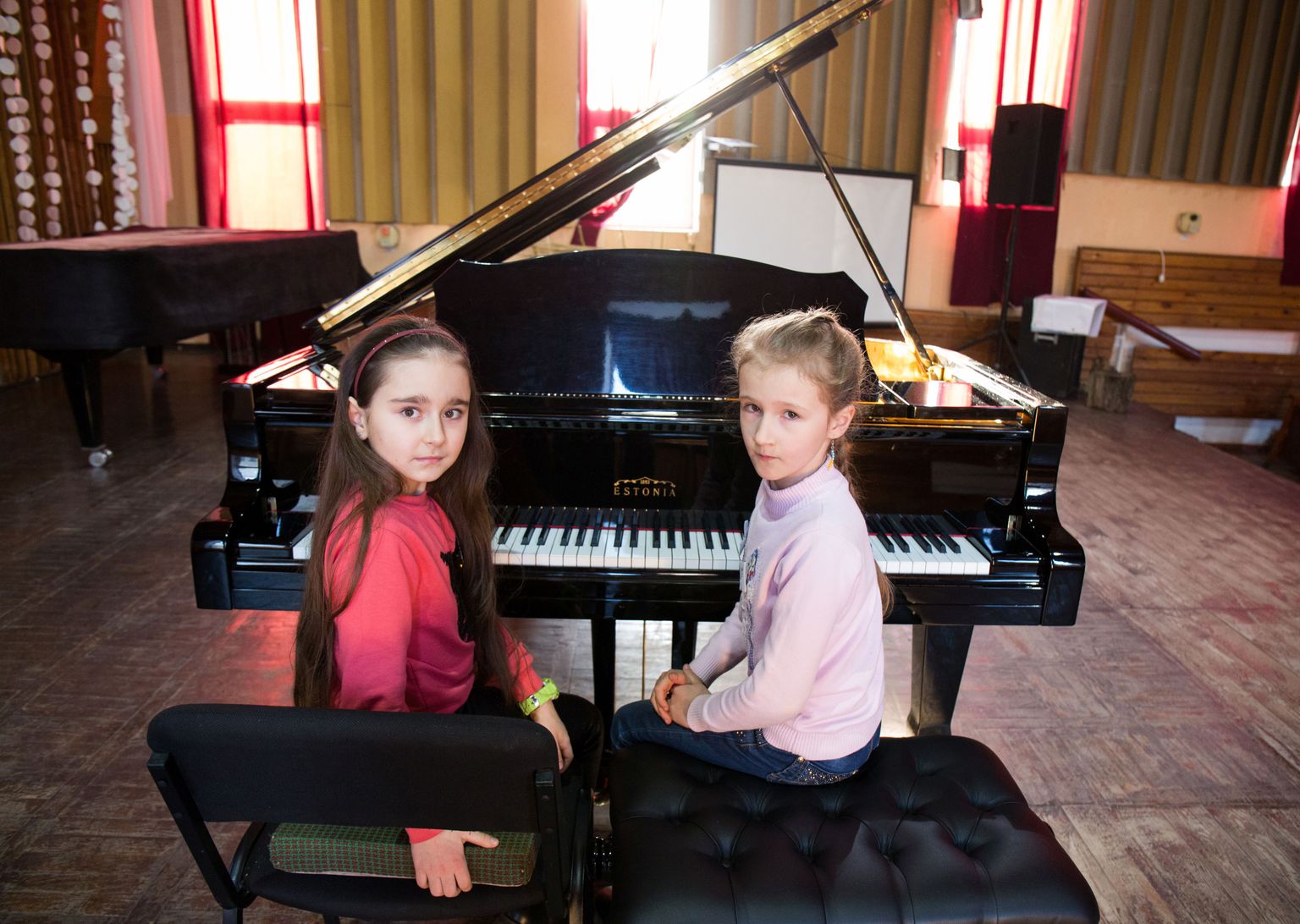 Üheksa-aastane Nastja (vasakul), aasta noorem Maša ja Estonia klaver Slovjanski kunstikooli laval.