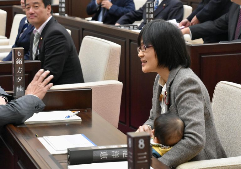 Kumamoto linnavolikogu liige istungi käigus last hoidmas.