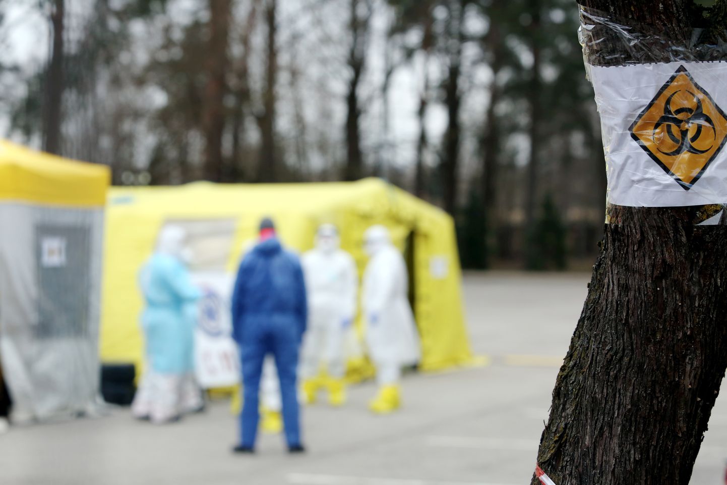 Mediķi aizsargtērpos pie telts Latvijas Infektoloģijas centrā, kurā iespēja nodot analīzes uz Covid-19.