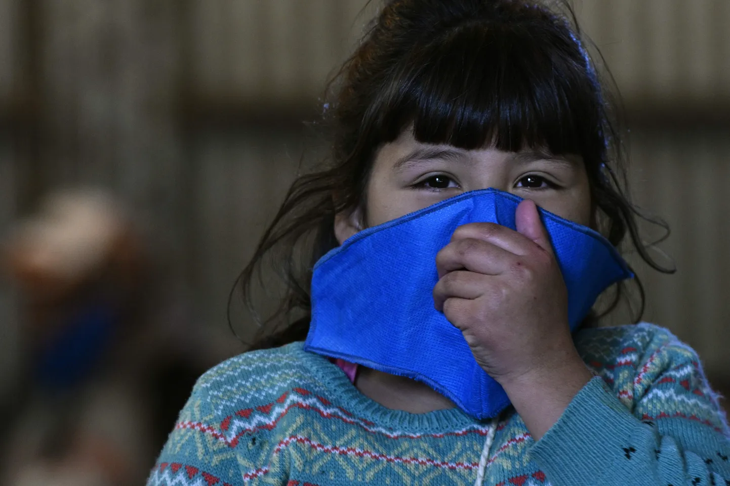 A girls wears a face mask against the spread of the new coronavirus, COVID-19 after having her afternoon milk at a community eatery during the lockdown imposed by the government in Jose C. Paz, Buenos Aires, Argentina, on May 8, 2020. - A replica of Argentina's football team jersey used during the final of the FIFA World Cup Mexico '86, handwritten and signed by Argentine former football star Diego Maradona, will be raffled among those who donate food to feed people at a working class neighbourhood called Rene Favaloro, after the Argentine cardiac surgeon. (Photo by JUAN MABROMATA / AFP)