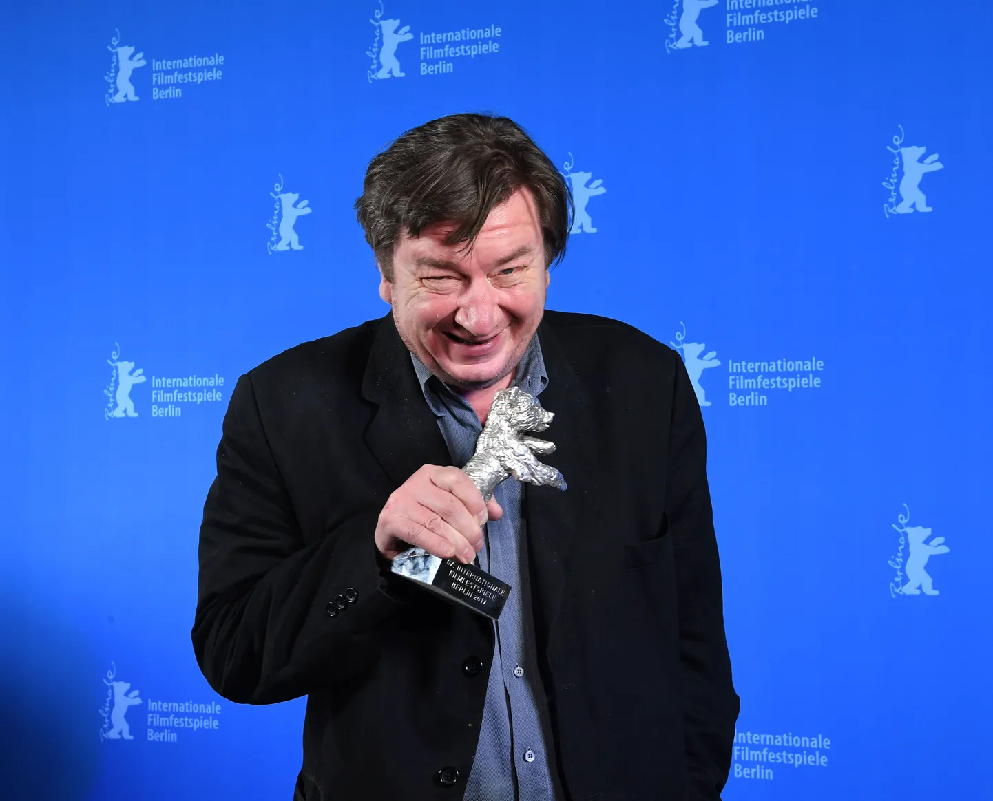 Aki Kaurismäki muheleb, Hõbekaru käes.