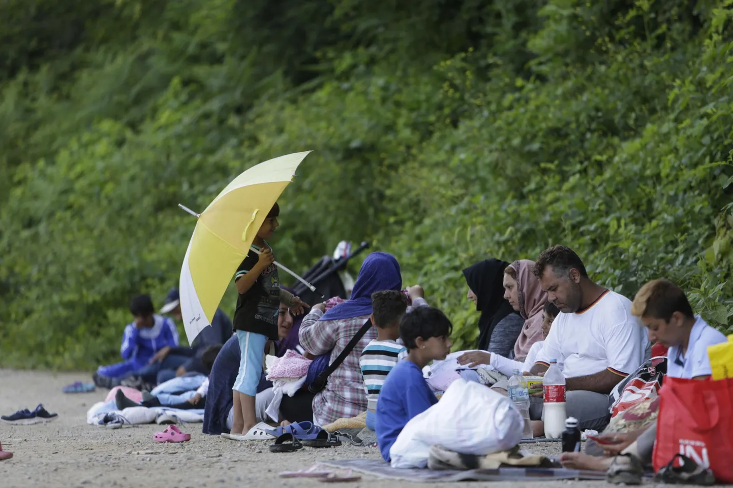 Bosnia väikelinnas Velika Kladušas pääseteed Horvaatiasse otsivad migrandid ootavad varjulises kohas toitu, mida jagavad neile kohalikud elanikud.