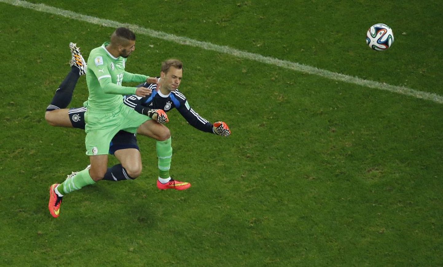 Saksamaa koondise väravavaht Manuel Neuer (paremal) on edestanud Alžeeria koondise ründajat Islam Slimanit ja löönud peaga palli alžeerlase eest ära.