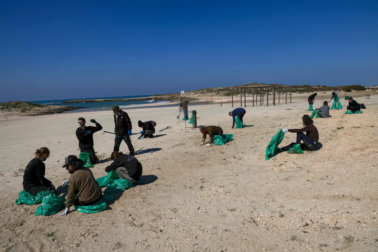 Волонтеры чистят загрязненный пляж, Израиль.