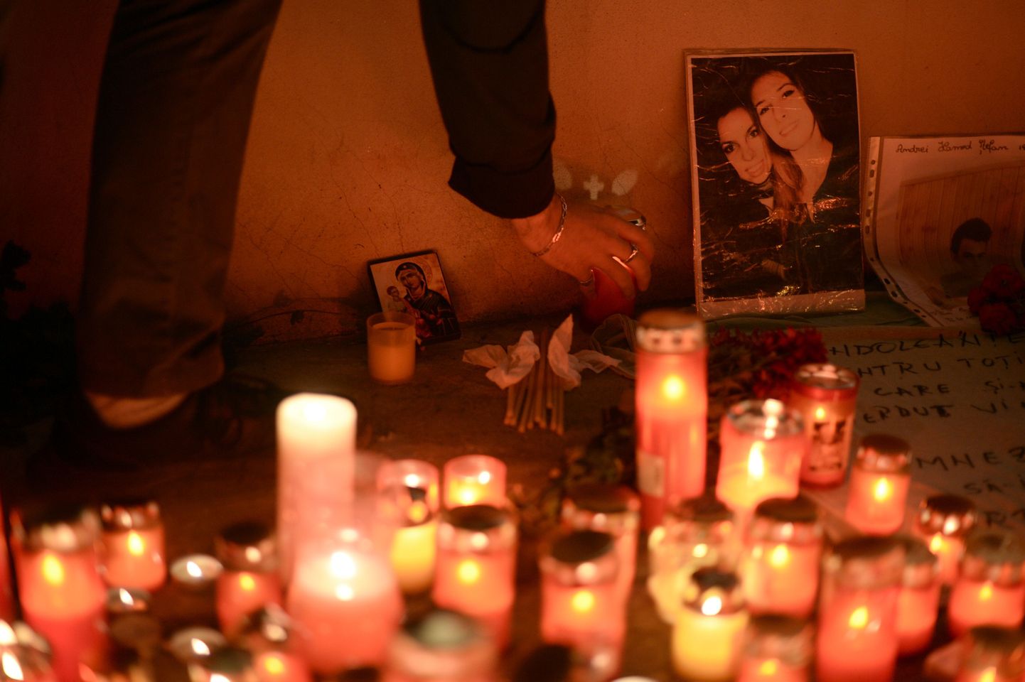 Люди приносят цветы и свечи в память погибших при пожаре в ночном клубе Бухареста.