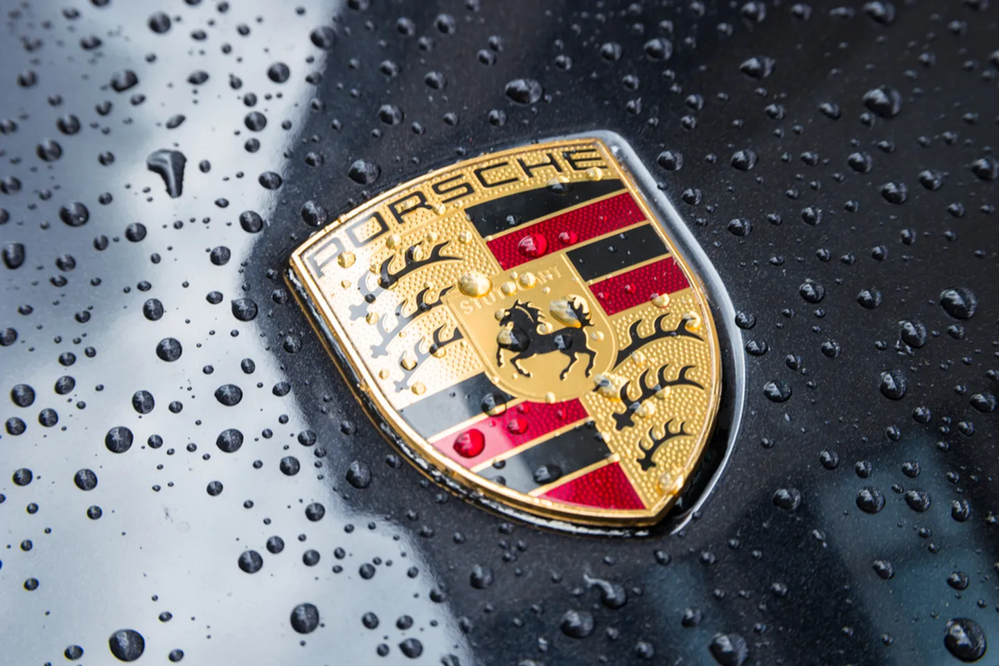 LONDON, UNITED KINGDOM MAY, 2017: Porsche Logo Close Up on a black car with rain drops. Ferdinand Porsche founded the company in 1931 with main offices in the centre of Stuttgart.
