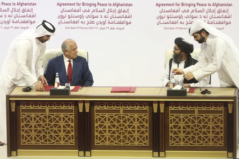 USA eriesindaja Zalmay Khalilzad (vasakul) ning Talibani poliitiline juhtkuju mulla Abdul Ghani Barada kirjutamas alla Doha leppele 29. veebruaril 2020. Leppe kohaselt viidi USA väed Afganistanist välja, vastutasuks pidi Taliban lubama, et Afganistani territooriumi ei kasutata enam eales terrorirünnakute läbiviimiseks.