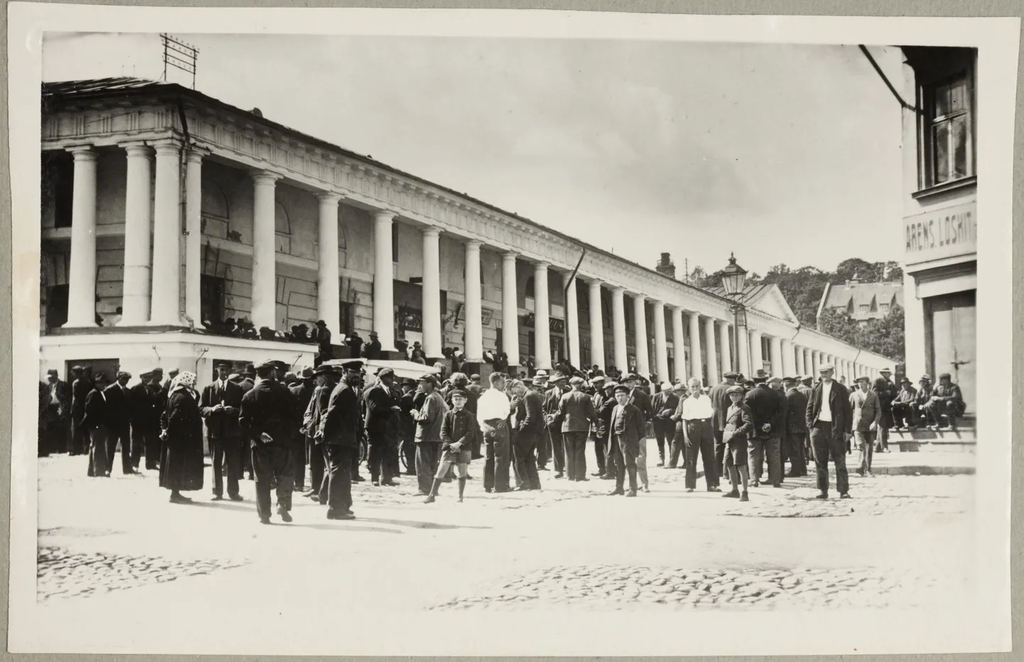 Sissepääs Rezvovi poodi asus Tartu kaubahoovi Poe tänava poolsel küljel. Seal tegutses ka nn orjaturg, kust tööandjad leidsid endale ajutist tööjõudu. Pildistatud ajavahemikus 1900–1917.