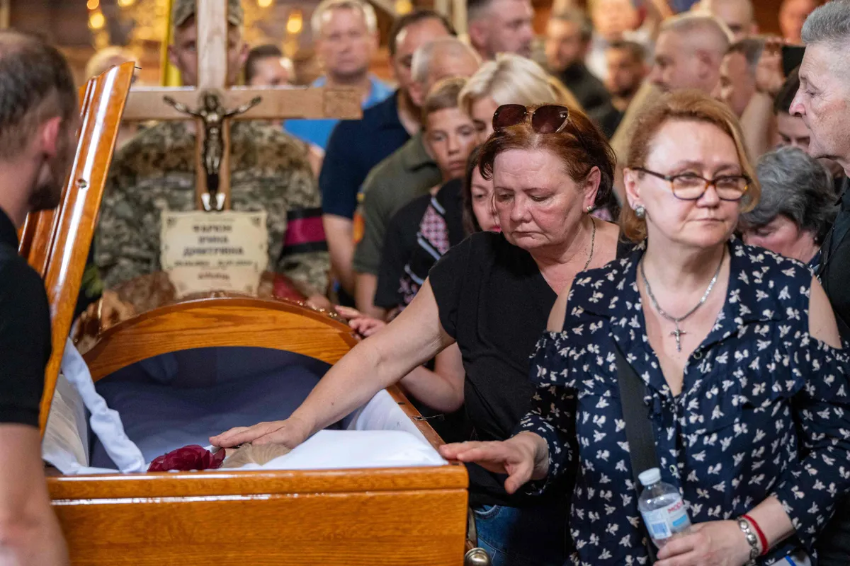 People mourn next to the coffin of former Ukrainian nationalist lawmaker Iryna Farion, who died after being shot by a gunman, during a funeral service at the Saints Peter and Paul Garrison Church in Lviv on July 22, 2024.