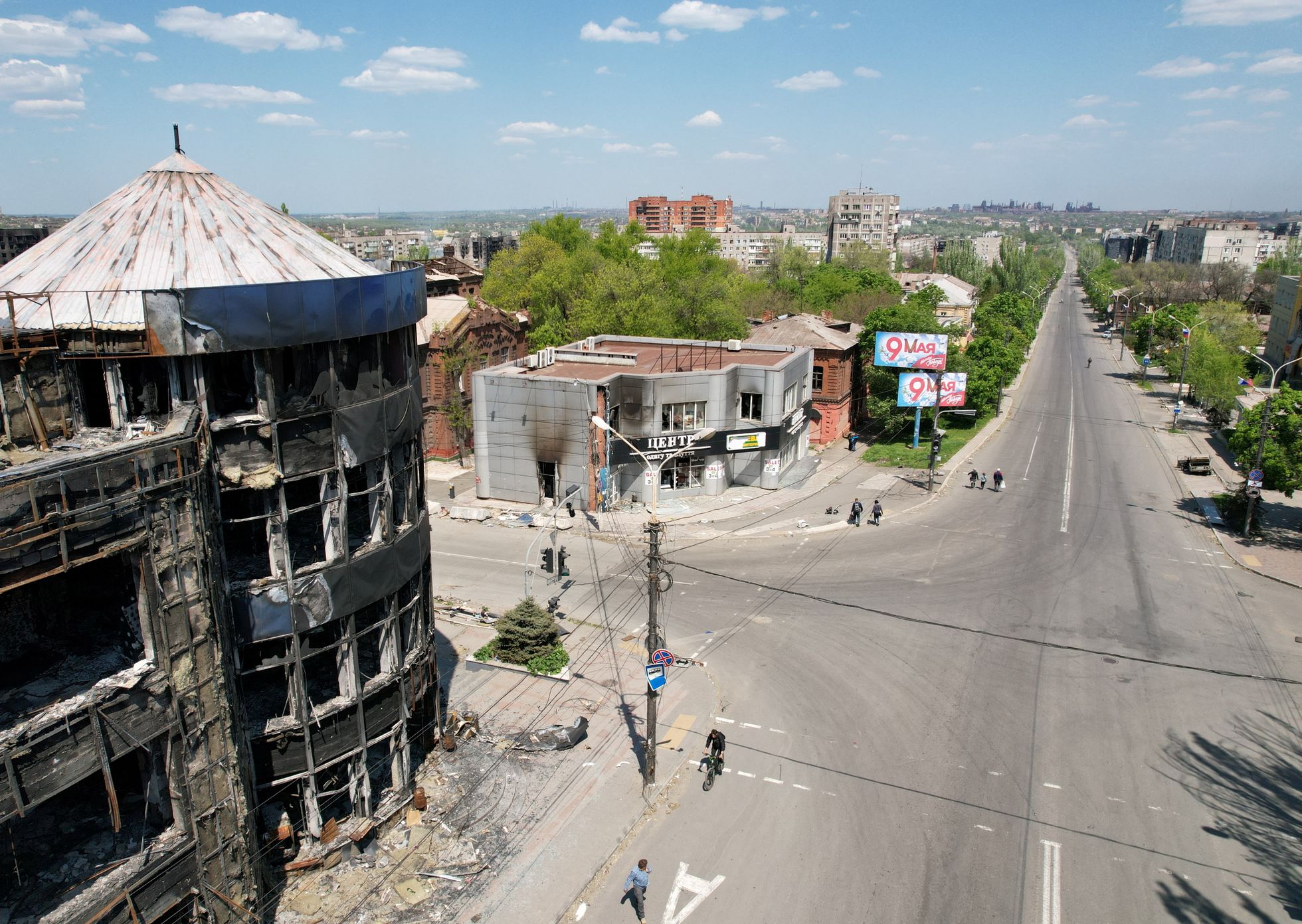 Purustatud hooned tänava ääres Mariupolis, kuhu olid tänaseks üles seatud võidupüha meenutavad plakatid.