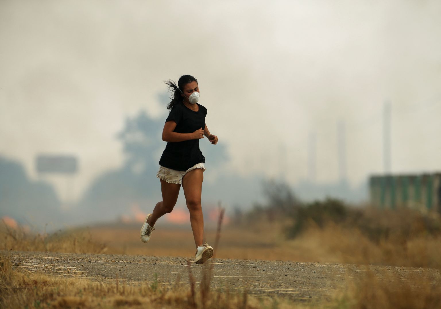 A girl runs away from a fire in a wheat field in Tabara, Zamora, on the second heatwave of the year, in Spain, July 18, 2022. REUTERS/Isabel Infantes