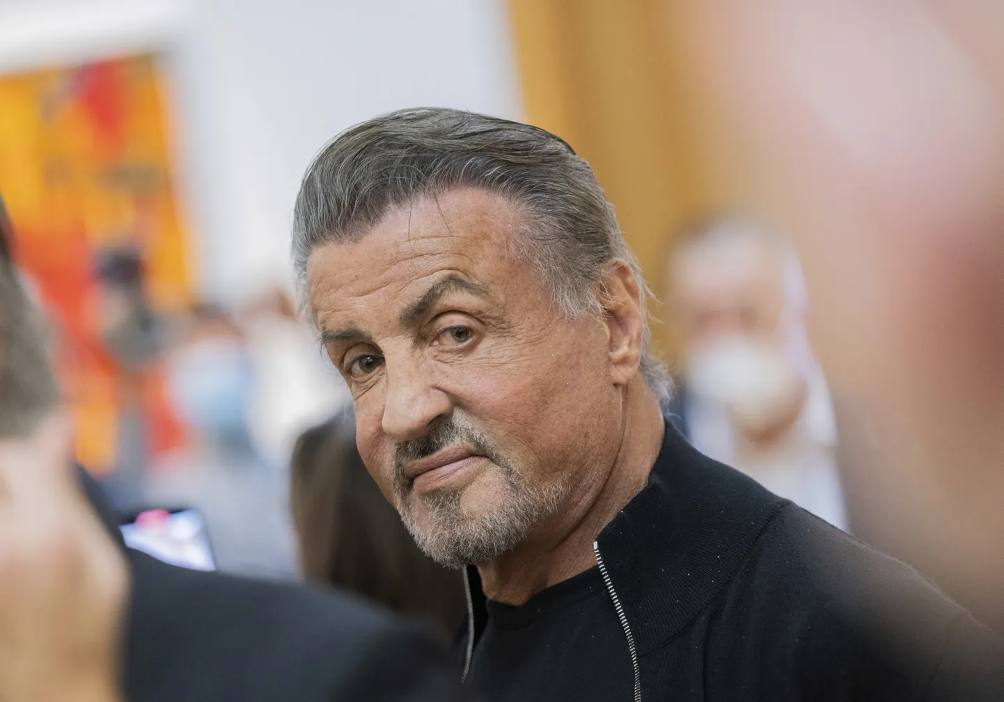 Sylvester Stallone, actor and painter, sits in the exhibition "Sylvester Stallone - 75th Birthday Retrospective" at the Osthaus Museum in Hagen, Germany, Dec. 3, 2021. The Hollywood star Sylvester Stallone also has an artistic side. His work as a painter is now being shown in Germany for the first time - for the opening of the show he is coming personally to the Ruhr area in Hagen. (Rolf Vennenbernd/dpa via AP)