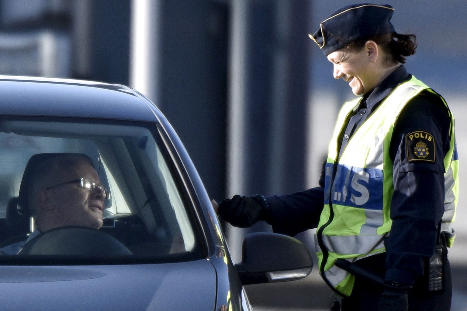 Rootsi politseinik kontrollimas riiki siseneva autojuhi dokumente.