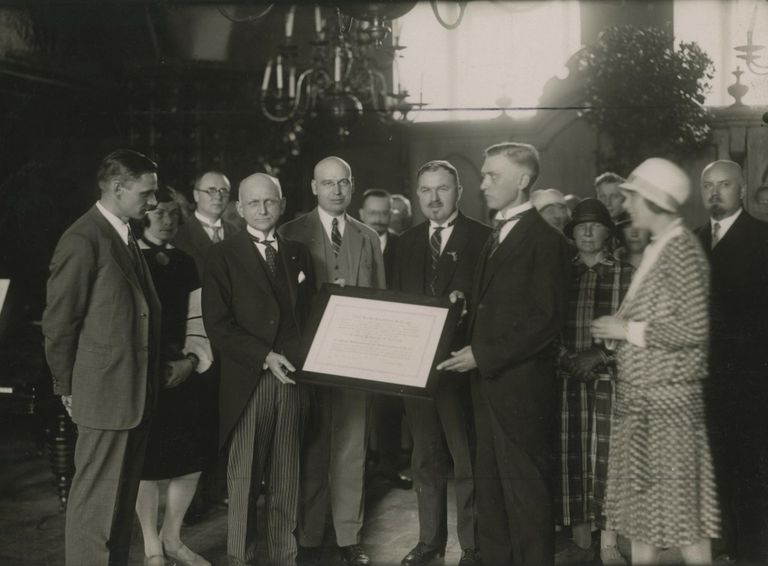 Ameerika Ühendriikide saadik Eestis Frederick Coleman (vasakul raamitud kirja hoidmas) andmas Tallinna linnapeale Anton Uessonile (paremal raamitud kirja hoidmas) üle Carnegie instituudi 1200-köitelise raamatukogu kingituskirja. Pilt on tehtud 30. juunil 1928.