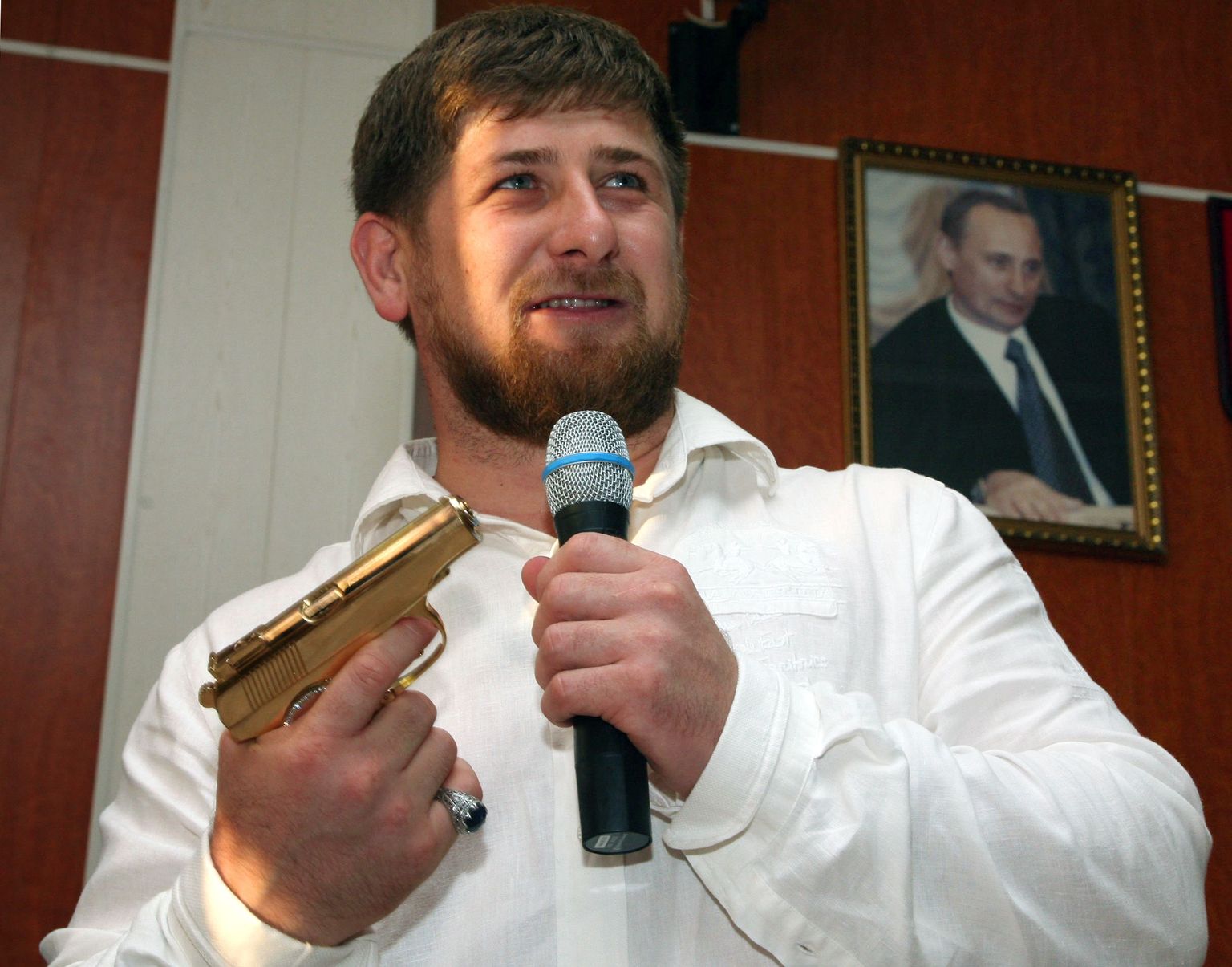 Ramzan Kadõrov kuldse relvaga. Seinal ripub Vladimir Putini pilt.