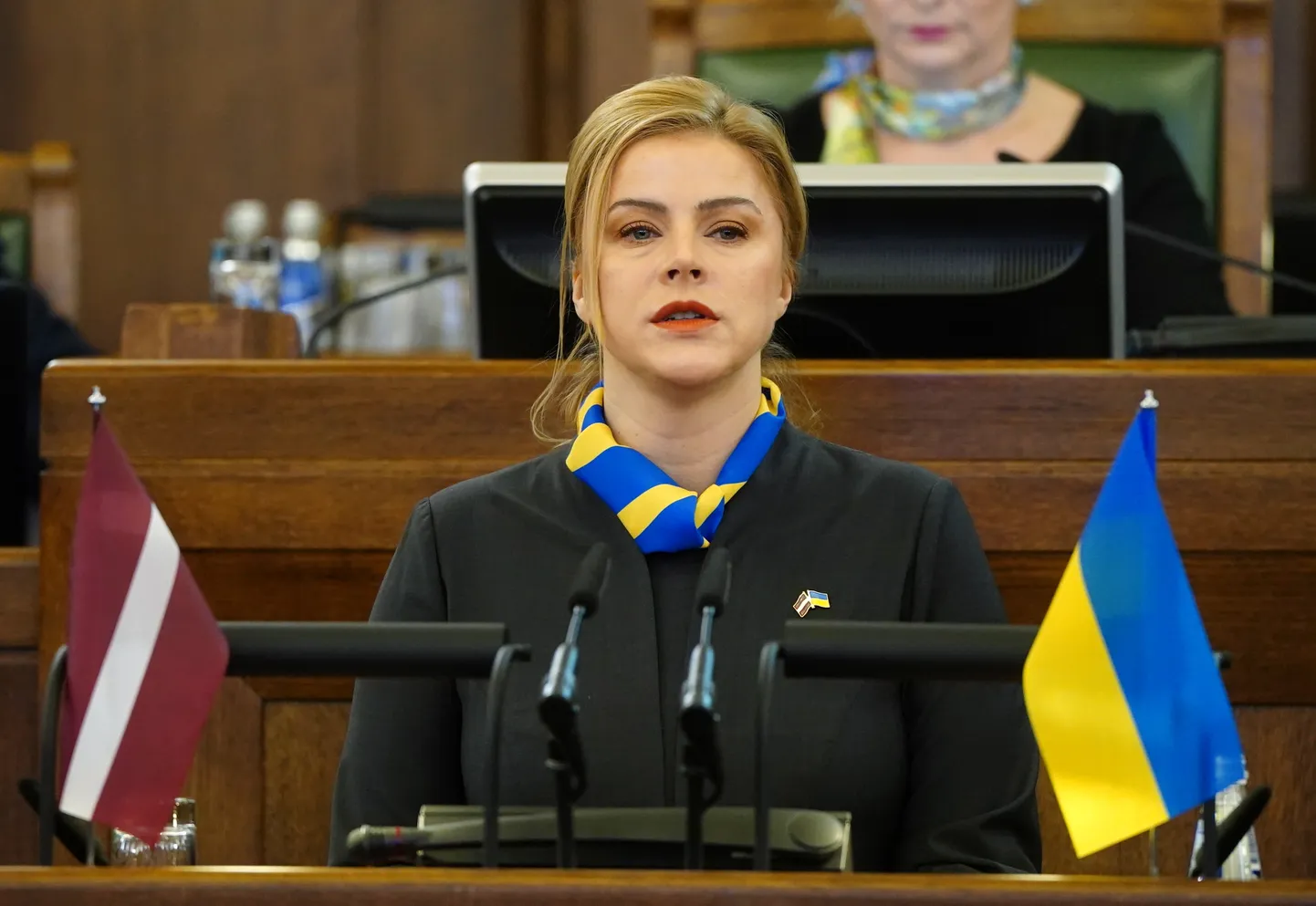 Ministru prezidente Evika Siliņa uzrunā klātesošos no tribīnes Saeimas ārkārtas sēdē, kurā piemin Krievijas pilna mēroga militārā iebrukuma Ukrainā otro gadadienu.
