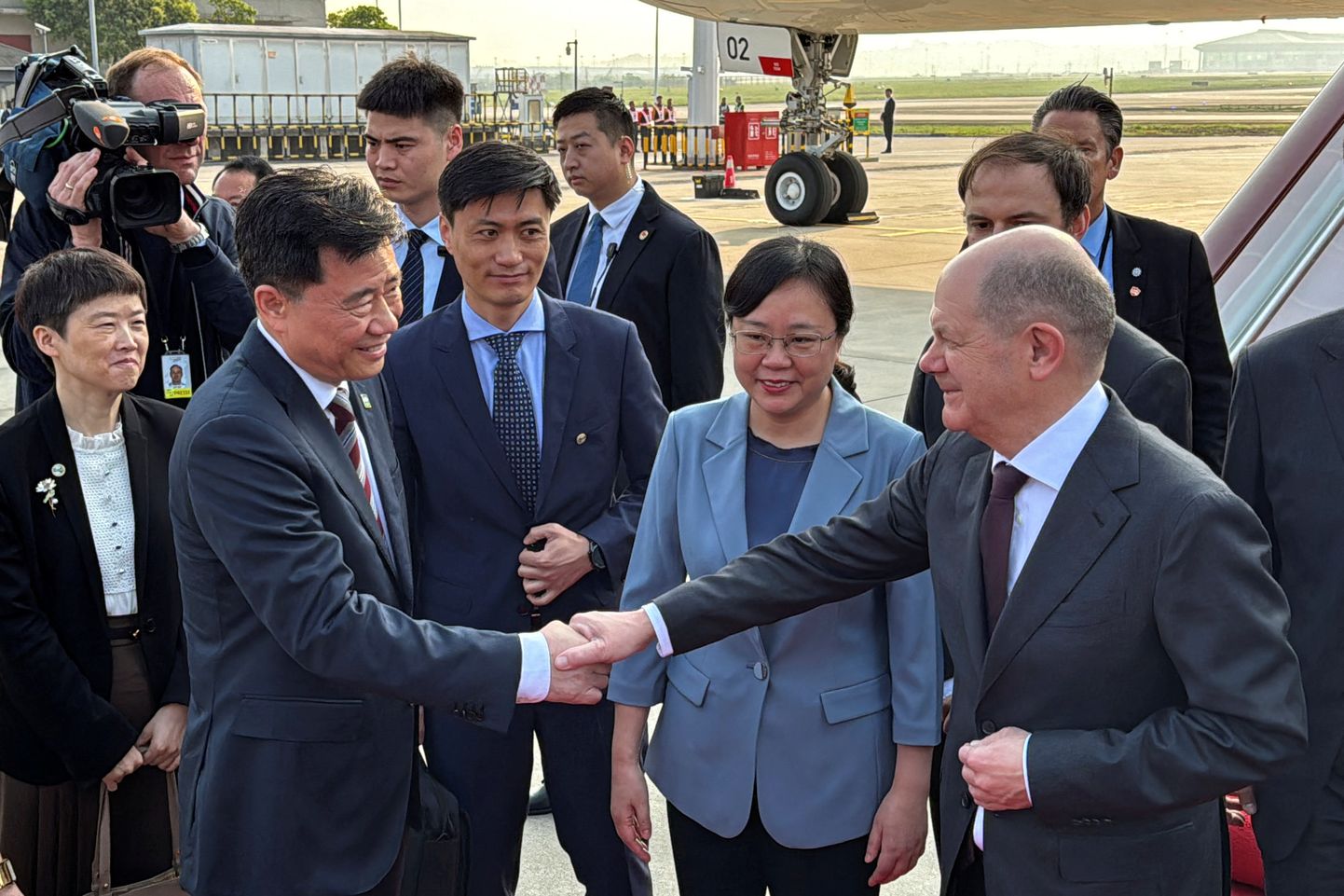 Saksa liidukantsler Olaf Scholz surub kätt Hiina suursaadikuga Saksamaal Wu Keniga, kelle kõrval seisab Chongqingi asemeer Zhang Guozhi. Scholz saabus Chongqingi lennujaama 14. aprillil ning ta külastas linnas ka Boschi tehast.