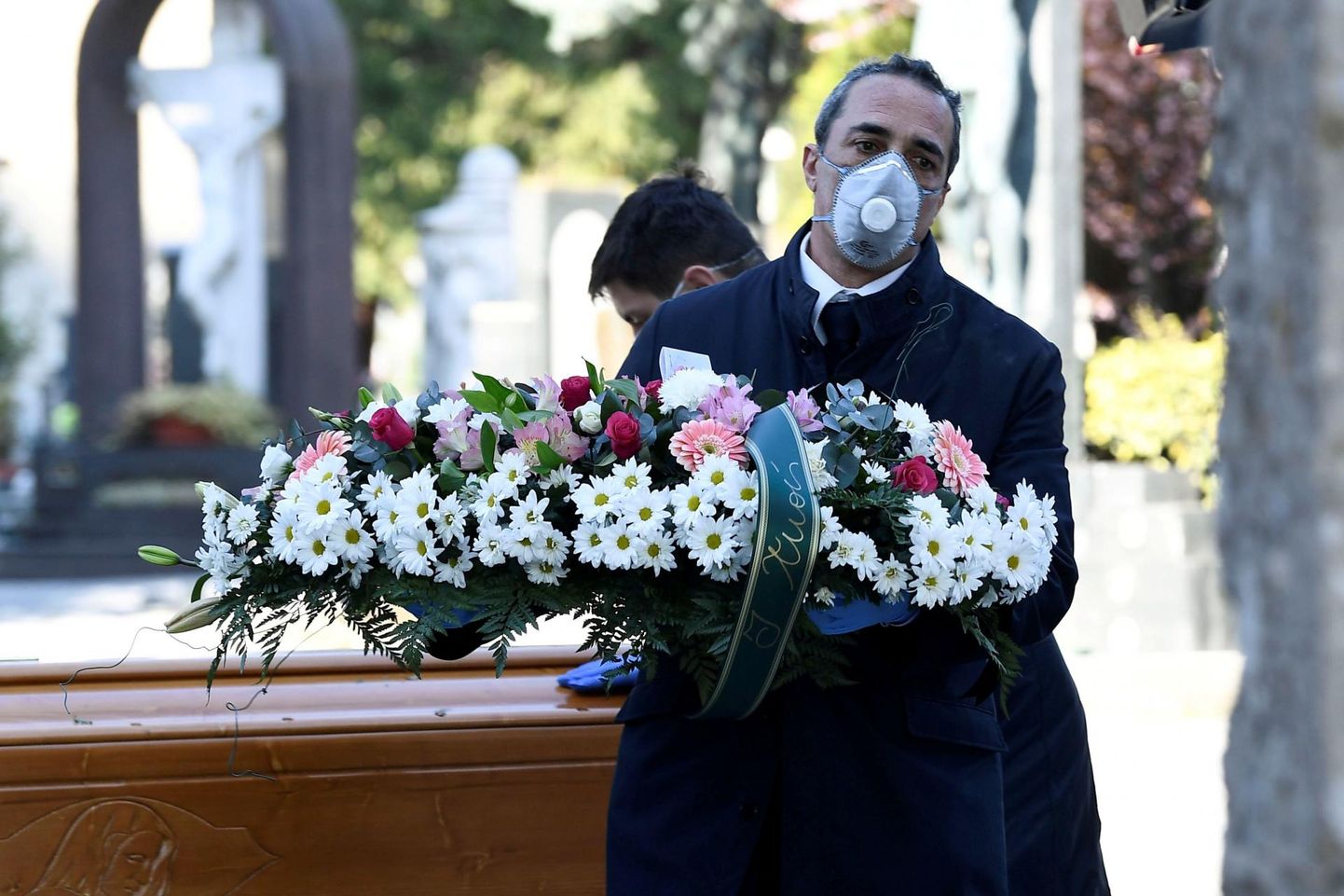 Bergamo surnuaiatöötaja kandmas kätel lilli ja näo ees maski. Euroopa riikidest on kõige rohkem surmajuhtumeid olnud just Itaalias. 