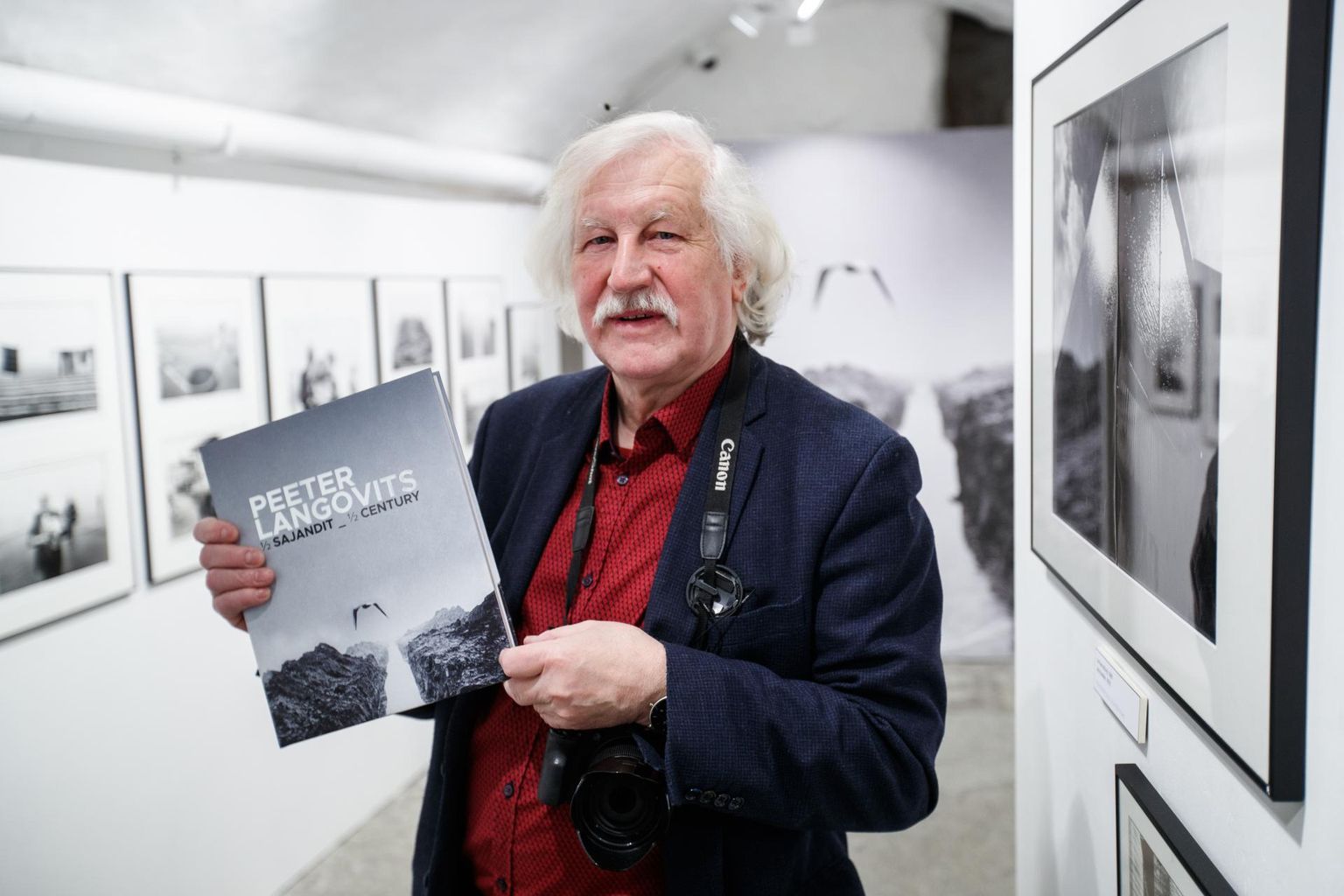 Peeter Langovits koos vastilmunud raamatuga oma näitusel Fotomuuseumis, ümbritsetuna 80ndate alguse Õismäest.