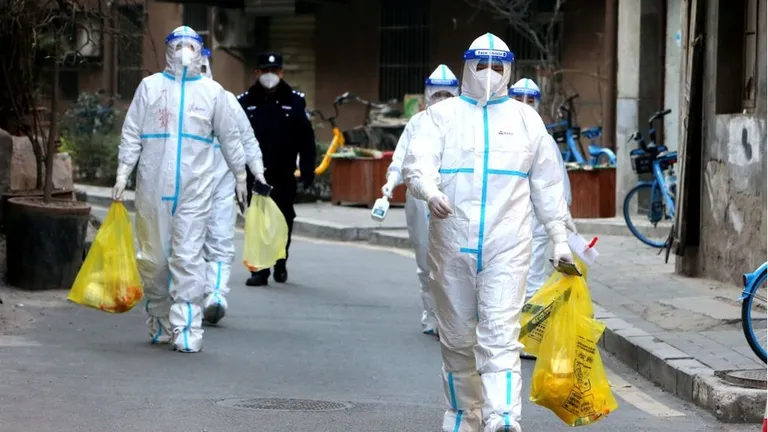 Staff members in protective suits as they test people in Xi