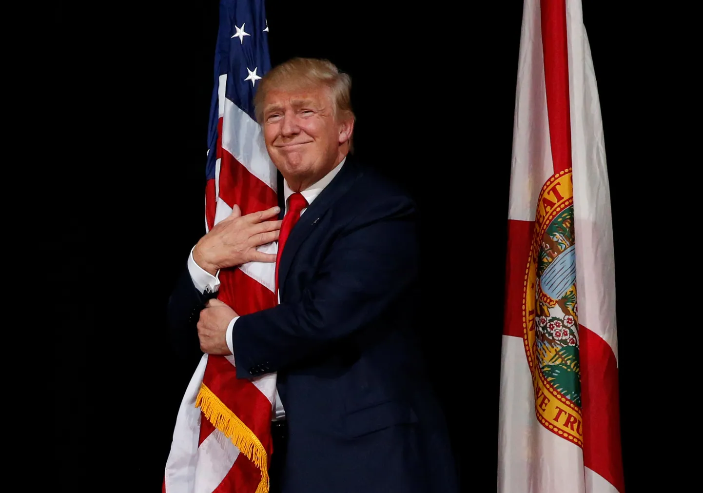 Donald Trump Ameerika Ühendriikide lippu kallistamas.