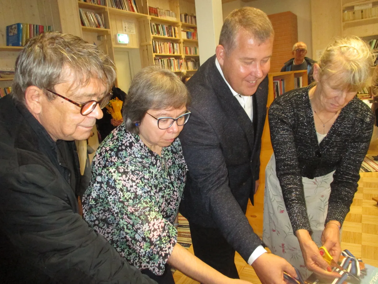 LUGEMISTUBA ON AVATUD Lindi lõikavad läbi oma uut raamatut esitlenud Olavi Antons, keskraamatukogu pearaamatukoguhoidja Maire Rauk, Saaremaa valla abivallavanem Koit Voojärv ja maja perenaine Elje Pihl.